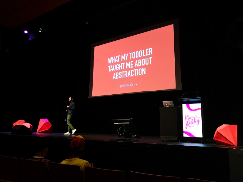 The Kiwi Ruby conference stage setup with illuminated podium in the foreground and a large presentation in the background